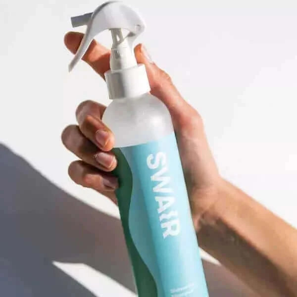 Woman holding Showerless Shampoo on white background